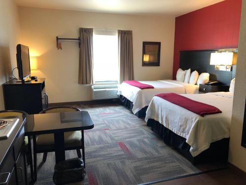 a hotel room with two beds and a desk at Black Gold Suites Tioga in Tioga