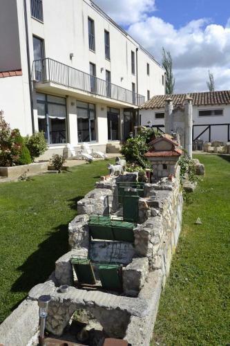 a stone retaining wall with green chairs in front of a building at Amanecer en Campos in Población de Campos