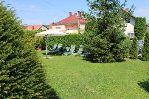 a group of chairs and an umbrella in a yard at Erika Apartmanházak in Hévíz