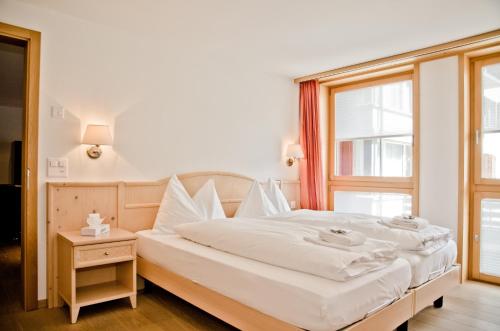 Schlafzimmer mit einem Bett mit weißer Bettwäsche und einem Fenster in der Unterkunft Apartment Stotzhalten 2.5 - GriwaRent AG in Grindelwald