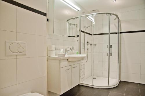 baño blanco con ducha y lavamanos en Apartment Stotzhalten 2.5 - GriwaRent AG, en Grindelwald