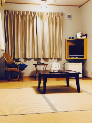 a living room with a coffee table and a television at まなべ旅館 in Sukumo