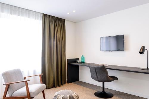 a room with a desk with a tv and two chairs at Hotel Nelson in Knokke-Heist