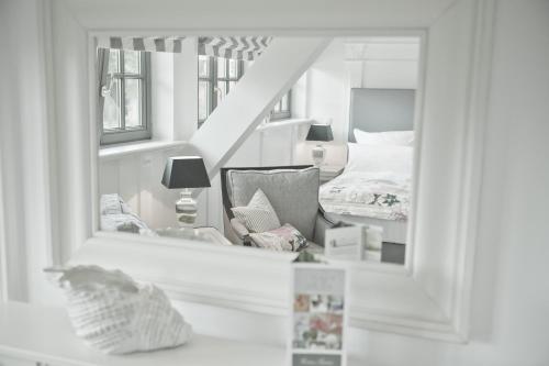 a mirror reflecting a bedroom with a bed and a chair at Landhaus Töpferhof bei Travemünde in Travemünde