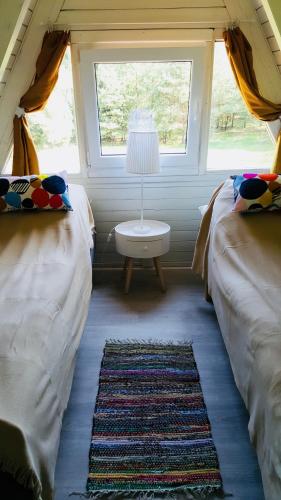 a room with two beds and a table with a window at Domek Przy Lesie in Kurzętnik