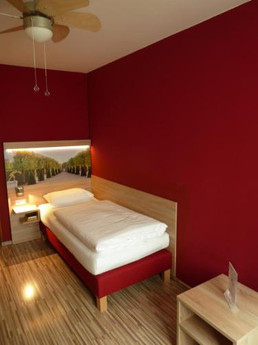 a red bedroom with a bed and a red wall at City Hotel Hannover in Hannover