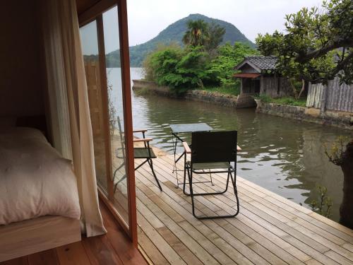 a room with a bed and a table and chairs on a deck at Waterside Cottage Heron in Kyotango