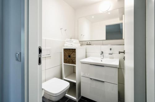 een witte badkamer met een toilet en een wastafel bij FeWo Prora - Hygge in Binz