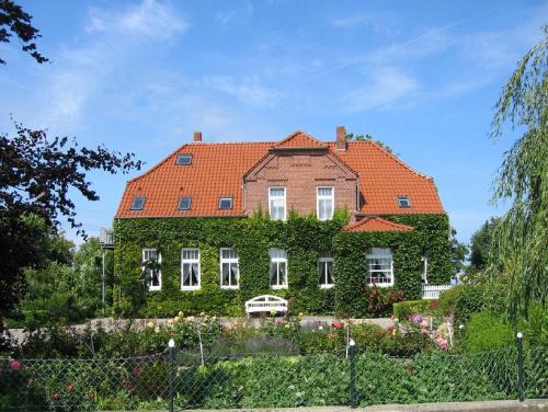 a house covered in ivy in front of a fence at Gästehaus Muhl in Strukkamp auf Fehmarn