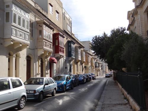 uma fila de carros estacionados numa rua da cidade em Granny's Inn Hostel em Sliema