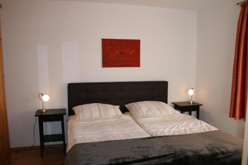 ザンクト・ペーター・オルディングにあるNickelshus-Whg-Birteのベッドルーム1室(ベッド1台、ランプ2つ、テーブル2台付)