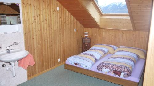 Dormitorio pequeño con cama y lavamanos en Gasthaus Bergheim, en Gurtnellen