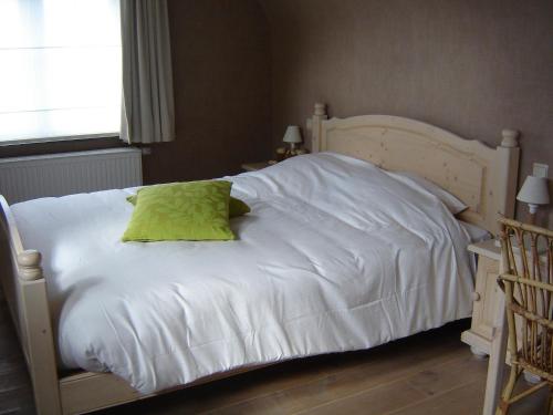 a white bed with a green pillow on it at B&B Wisteria in Herne