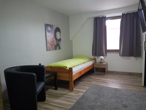 ein Schlafzimmer mit einem Bett, einem Stuhl und einem Fenster in der Unterkunft Gasthof Wolfs Stuben in Reichenbach an der Fils