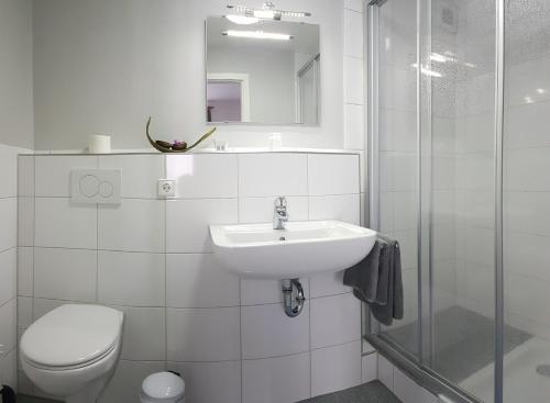 a white bathroom with a sink and a toilet at Gasthof Wolfs Stuben in Reichenbach an der Fils
