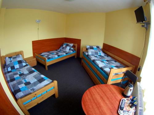 Cette chambre comprend 3 lits et une table. dans l'établissement Noclegi Wega, à Częstochowa
