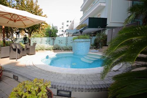 ein kleiner Pool auf einer Terrasse mit Sonnenschirm in der Unterkunft Hotel Derby in Rimini