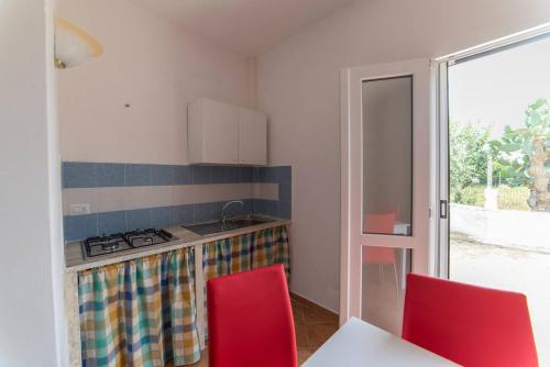 una cucina con piano cottura e 2 sedie rosse di Alloggi in Villa Potenza a pochi minuti da Gallipoli a Galatone
