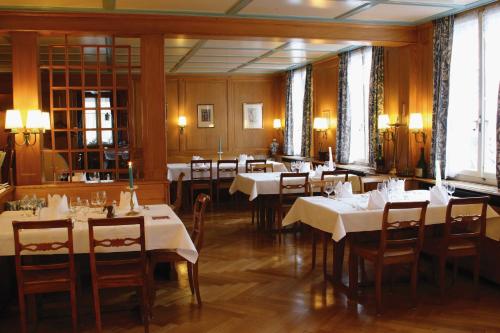 a dining room with tables and chairs with white tablecloths at Gasthof Bären Laupen in Laupen