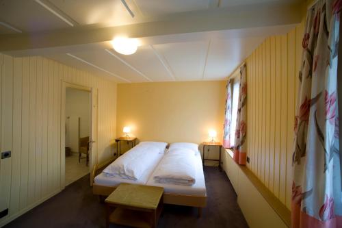 a bedroom with two beds in a room with yellow walls at Gasthof Bären Laupen in Laupen