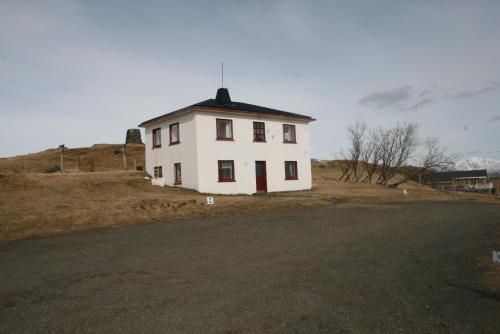 a white house on the side of a road at Guesthouse Holmur in Hólmur