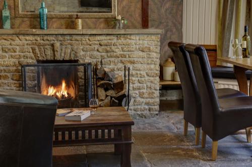a living room with a fireplace and a table and chairs at Best Western Compass Inn in Tormarton