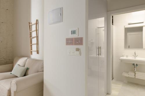 a white bathroom with a couch and a sink at Luces de Catedral in Alicante