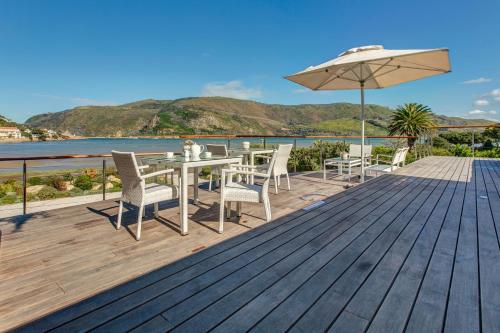 a wooden deck with a table and chairs and an umbrella at Amanzi Island Boutique Hotel in Knysna