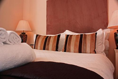 a bedroom with a bed with two striped pillows at Annandale Arms Hotel in Moffat