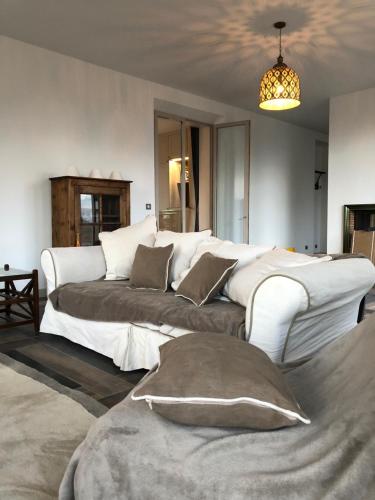 - un salon avec un grand canapé blanc et des oreillers dans l'établissement Exceptionnel, 130 m2, vue aérienne sur Paris, à Ville-dʼAvray