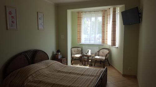 een slaapkamer met een bed en 2 stoelen en een raam bij Posejdon in Ustronie Morskie