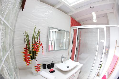 uma casa de banho branca com um lavatório e um chuveiro em Le Talisman em Goyave