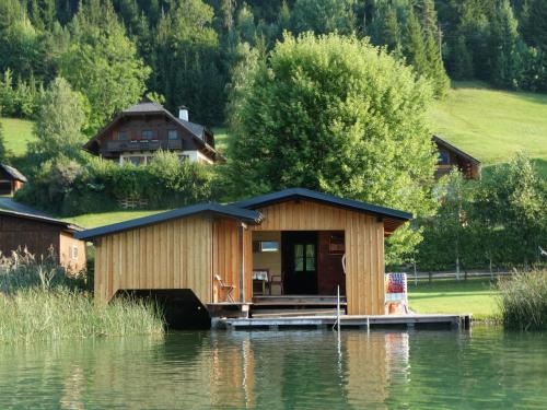 a cabin on a dock on a body of water at Glautschhof in Weissensee