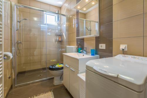 a bathroom with a shower and a sink and a toilet at Apartmani Lucić in Crikvenica