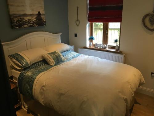 1 dormitorio con 1 cama blanca y 2 almohadas en The Olive Branch at The Poplars, en Kilgetty