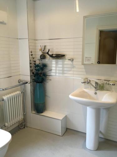 a white bathroom with a sink and a mirror at The Olive Branch at The Poplars in Kilgetty