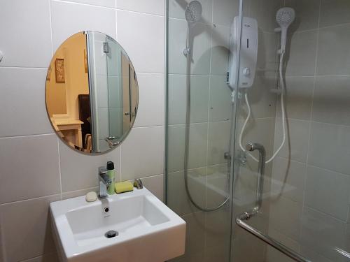 a bathroom with a sink and a shower with a mirror at SJA Suria Jelutong in Shah Alam