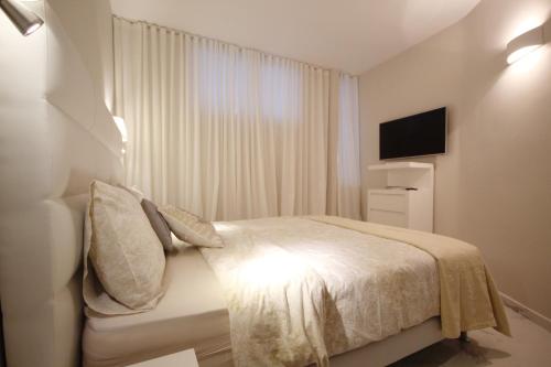 a white bedroom with a bed and a television at Luxury Apartments in first beach line with pool in Adeje