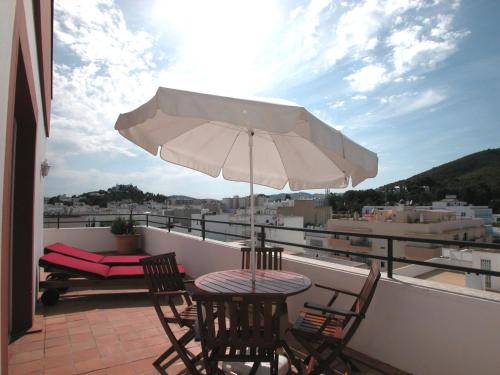 聖埃烏拉利亞的住宿－埃布索斯公寓，阳台配有桌椅和遮阳伞。