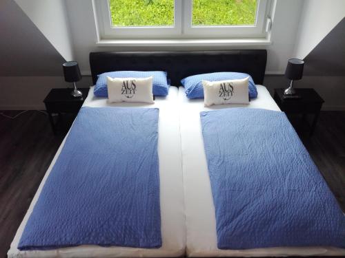 twee blauwe en witte bedden in een kamer met een raam bij Auszeit & Ankerplatz in Aurich