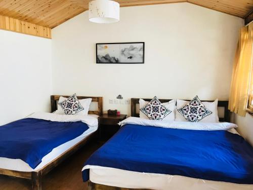 two beds in a room with blue and white at Tourist Courtyard Hotel in Jianchuan