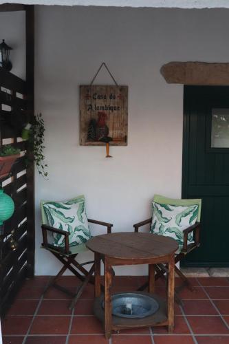 a wooden table and two chairs and a table and a door at Casa do Alambique in Tomar