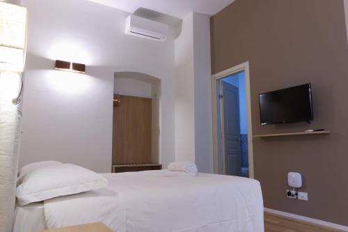 a bedroom with a white bed and a flat screen tv at B&B Castanea in Castellaneta