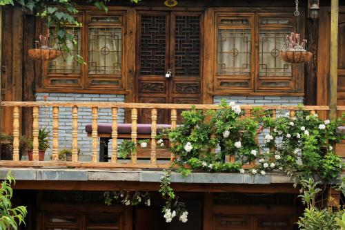 a wooden balcony with a bench and flowers on it at Tourist Courtyard Hotel in Jianchuan