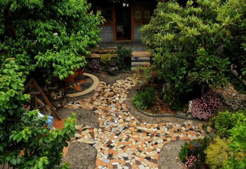 a garden with a stone path and trees at Tourist Courtyard Hotel in Jianchuan