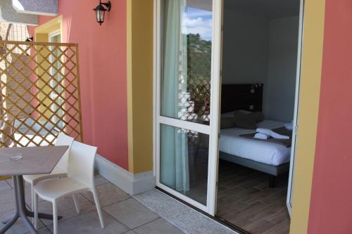 a balcony with a table and a room with a bed at Hotel Bocciolo in Orta San Giulio