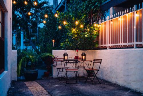 a table and chairs with lights on a fence at Renovated Historic Coconut Grove Cottage Home in Miami