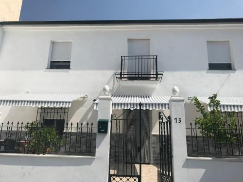 ein weißes Gebäude mit einem Tor und einem Balkon in der Unterkunft Casa Macetero en Granada in Granada