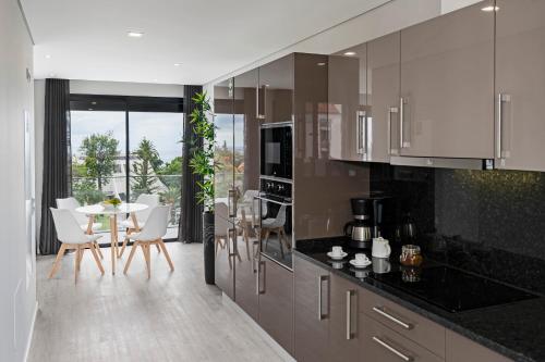 a kitchen with white cabinets and a table and chairs at Funchal Lux I by An Island Apart in Funchal