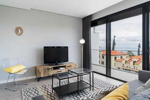 a living room with a tv and a large window at Funchal Lux I by An Island Apart in Funchal
